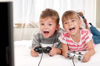 Young-boy-and-girl-lying-on-a-bed-enjoying-playing-video-games-together